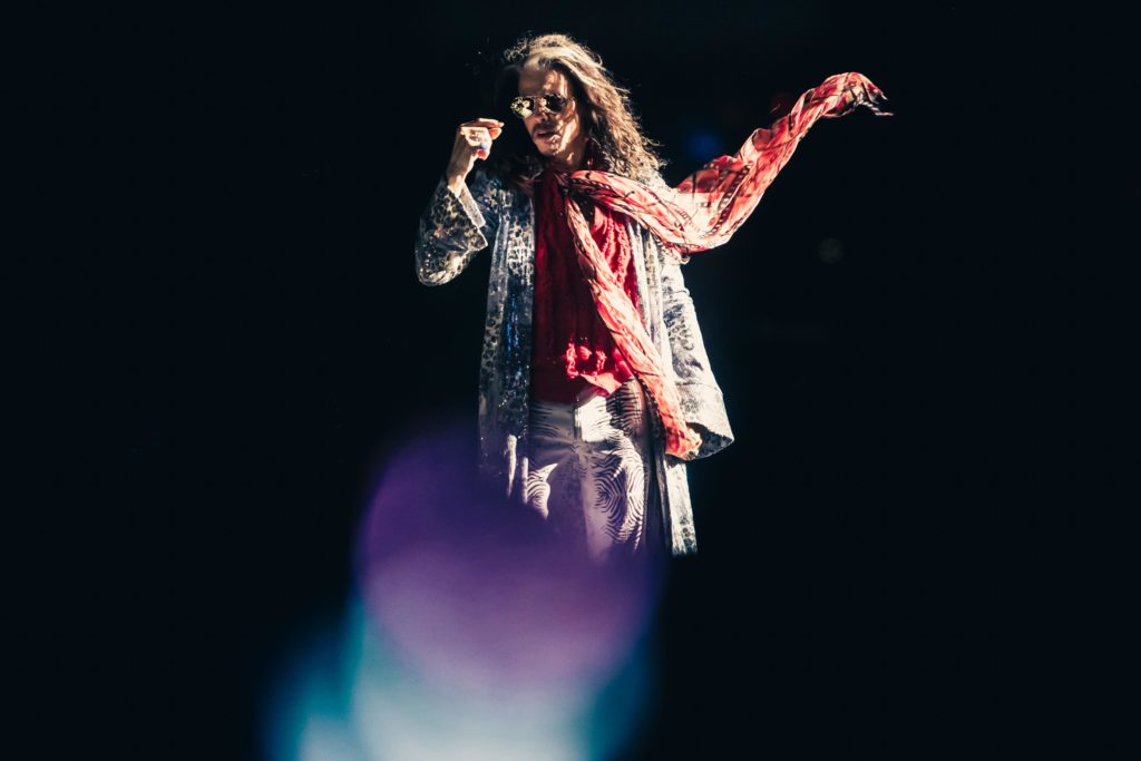 Steven Tyler with arms spread wide mid-performance