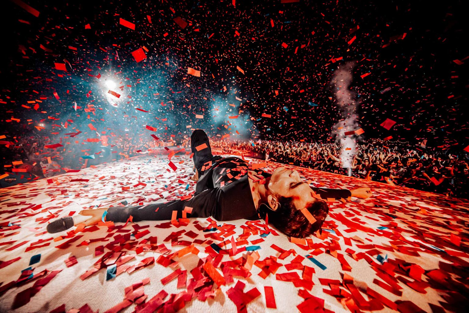 Aviv Geffen lying on a stage covered in red confetti