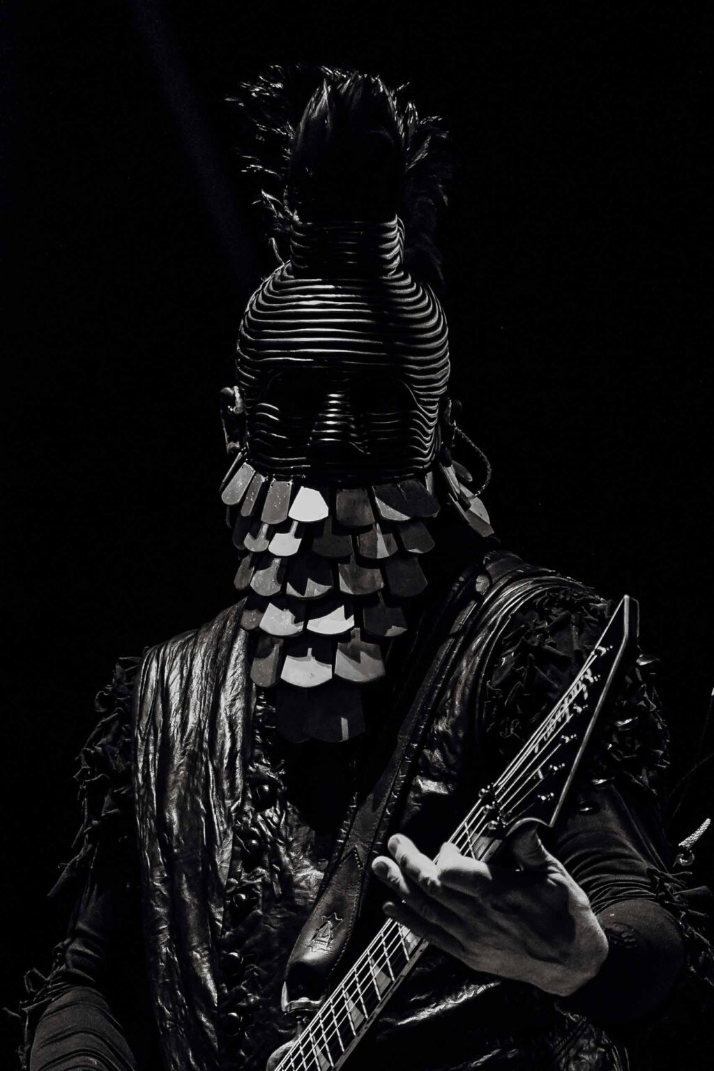 Wes Borland in an ornate black stage costume under a single spotlight