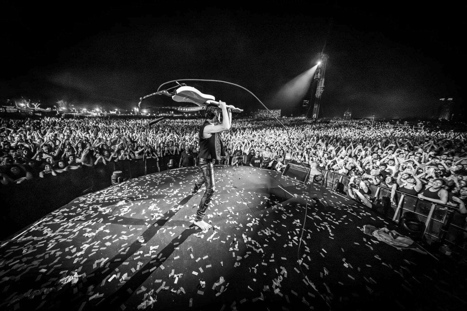 Aviv Geffen raising a guitar over his head before a festival crowd